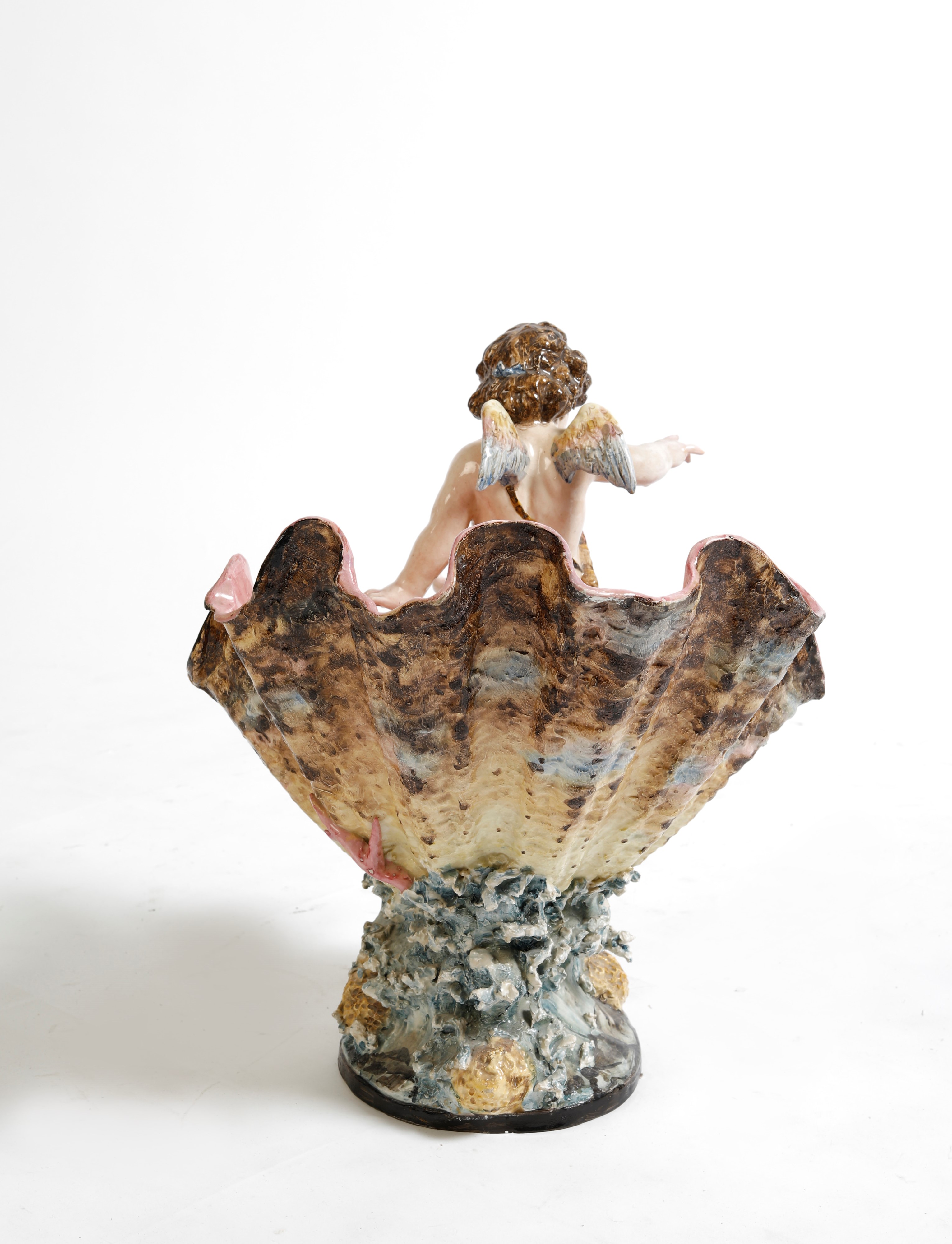 Centrotavola in ceramica policroma a foggia di conchiglia e putto